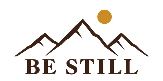 Designet på Be Still-capsen: BE STILL under en fjellsilhuett og en gyllen sol