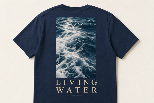 Marineblå t-skjorte sett bakfra med fotomotiv av havbølger over teksten LIVING WATER